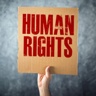 A hand holding up cardboard sign saying human rights